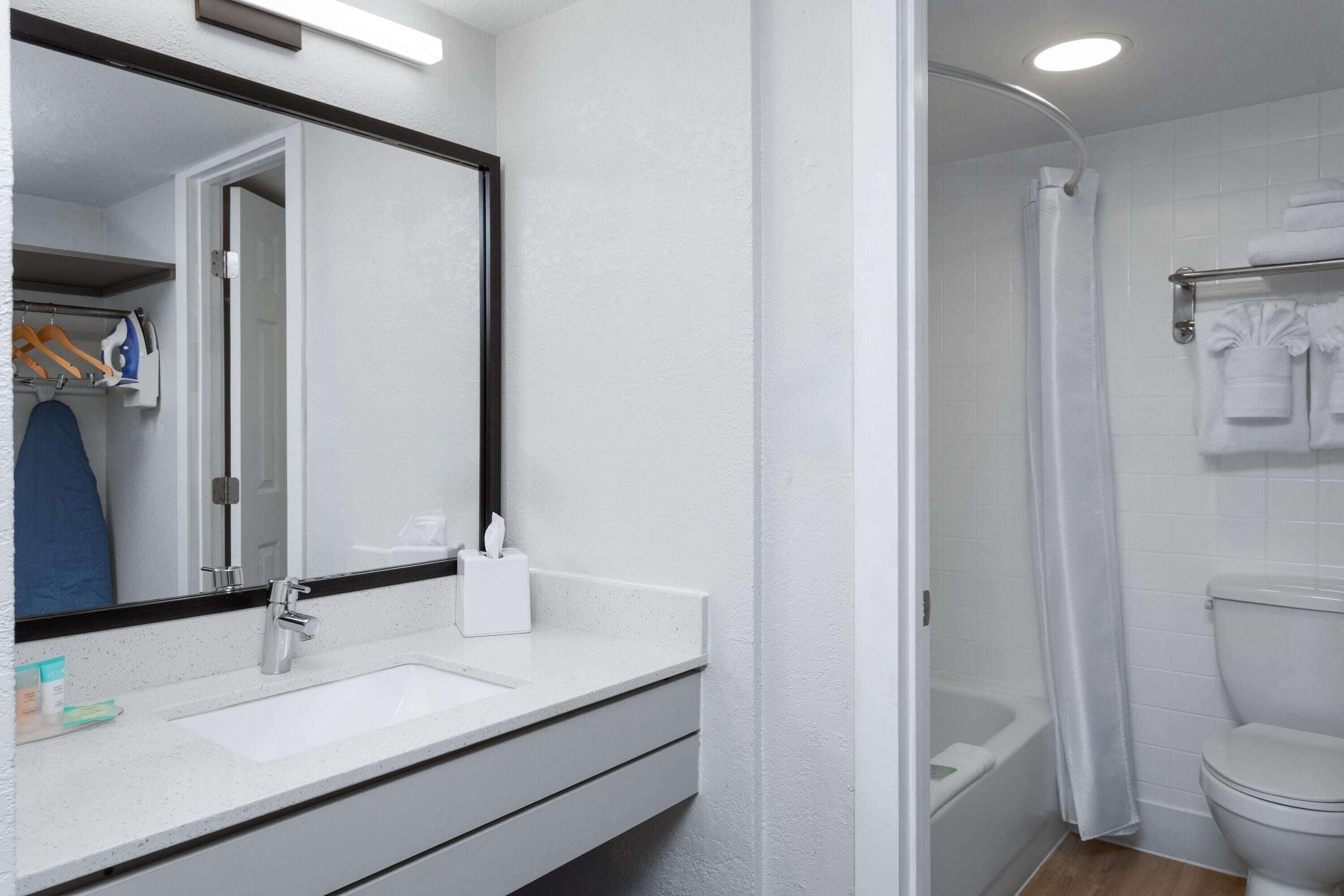 A bathroom with a white sink, mirror, and toilet.