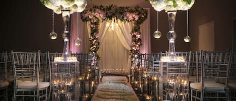 A wedding aisle with floral arrangements and chandeliers.