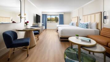 Una habitación de hotel moderna con una cama grande, un escritorio con silla, un sofá y un televisor.
