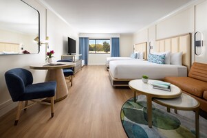 Una camera d'albergo moderna con un grande letto, una scrivania con una sedia, un divano e una televisione.