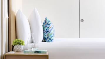A neatly arranged bedroom with a bed, bedside table, and a small potted plant.