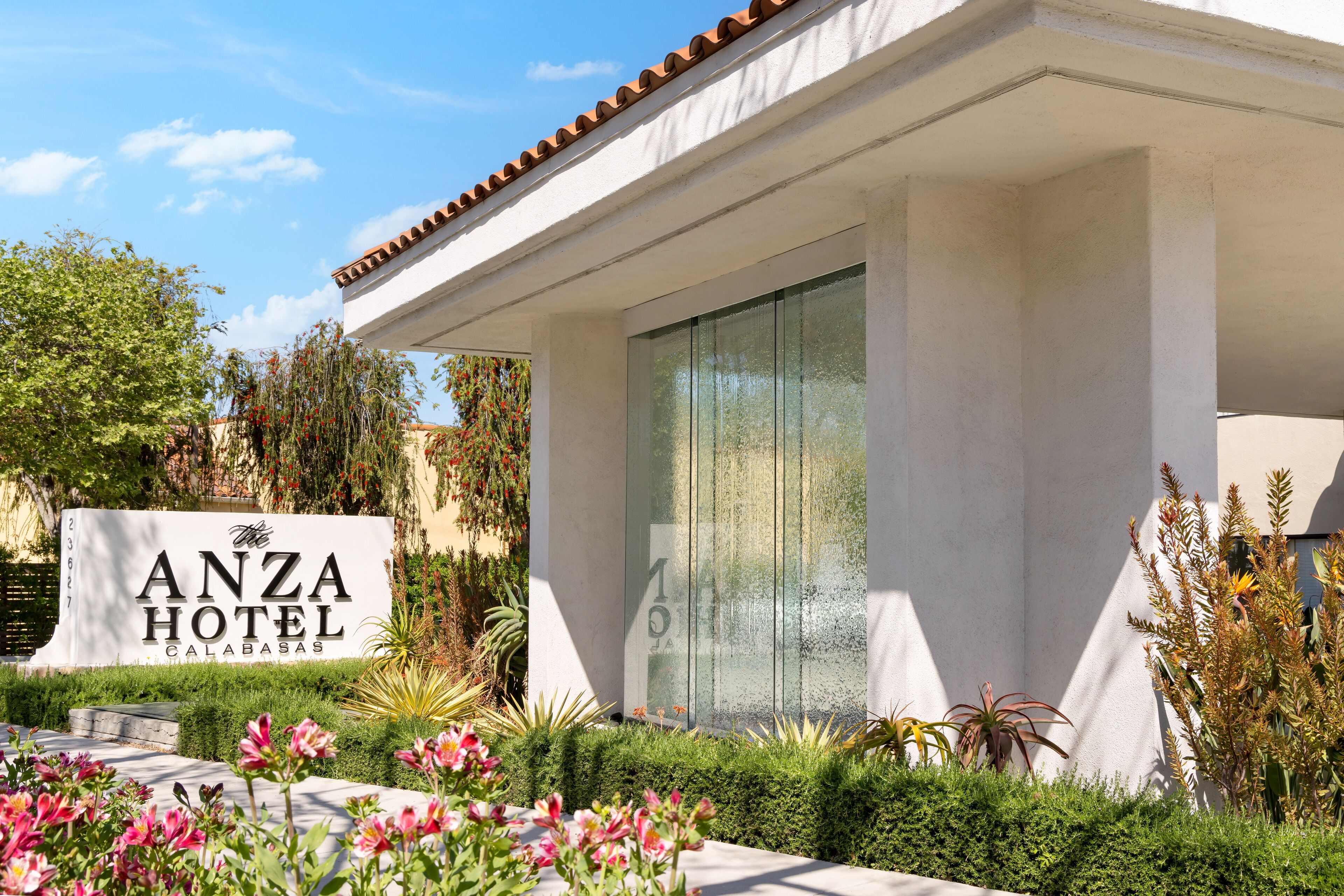 The exterior of the Anza Hotel with a sign, a covered entrance, and well-maintained landscaping.