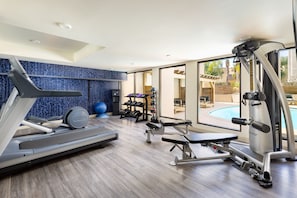 A modern gym with a treadmill, weight bench, and exercise machines. - The Anza - A Calabasas Hotel (Calabasas)