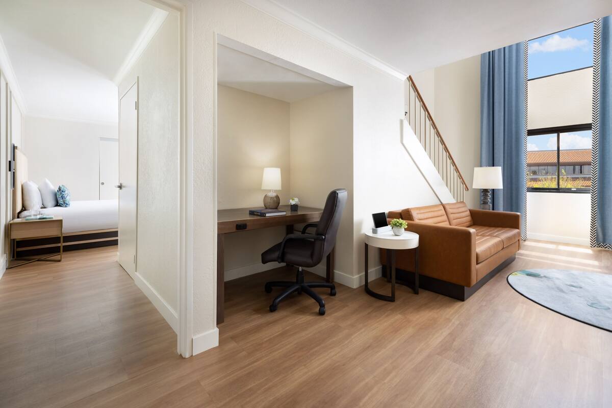 A hotel room with a bed, desk, office chair, and a sofa.