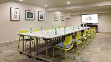 Une salle de conférence avec une longue table, des chaises jaunes et des bouteilles d’eau vertes.