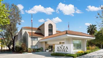 Hotel Anza, diseño moderno, con una entrada destacada, un asta de bandera y un jardín bien cuidado.