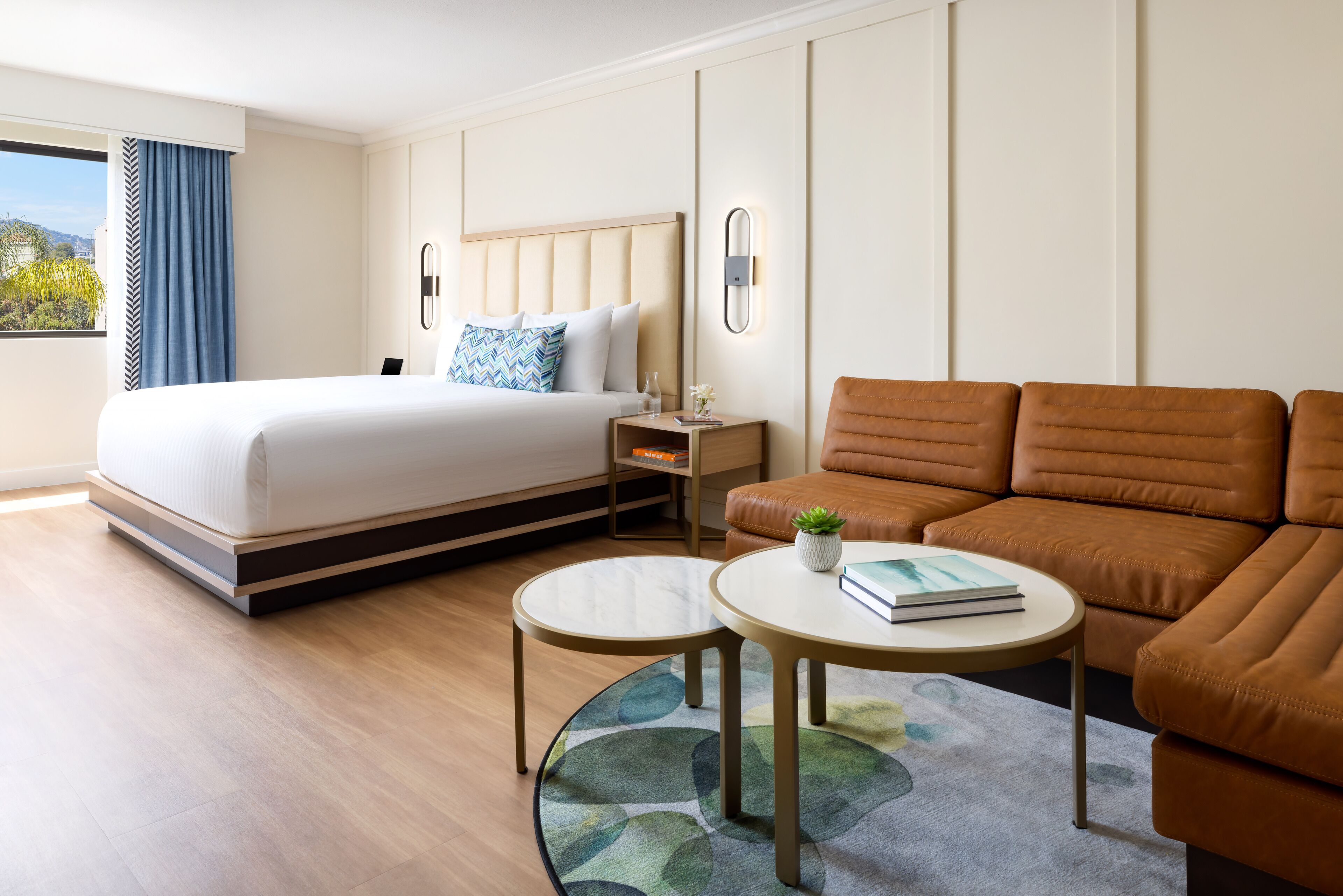 A hotel room with a bed, a sofa, a small table, and a nightstand.
