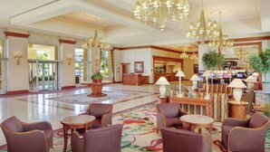 A spacious lobby with multiple seating areas, a reception desk, and a large chandelier. - Hilton Seattle Airport & Conference Center (SeaTac)
