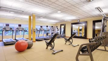 Un gimnasio con cintas de correr, elípticas y equipo de levantamiento de pesas.