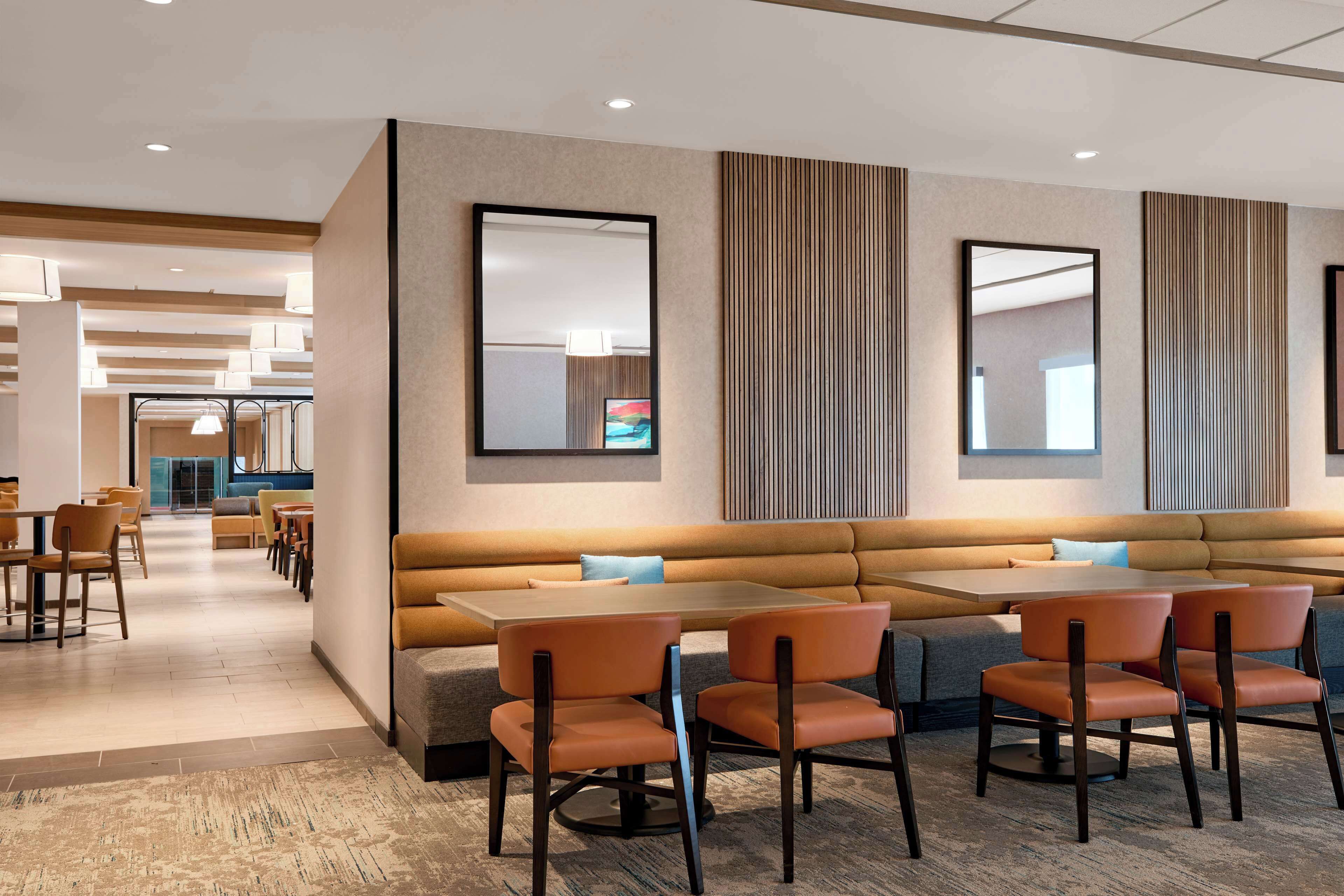 Un moderno vestíbulo de hotel con zona de estar, mesas y vistas al interior.