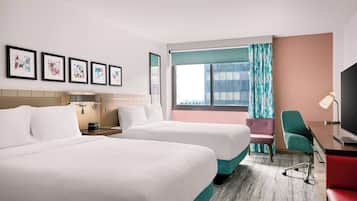 A hotel room with two beds, a desk, a chair, a TV, and artwork on the wall.