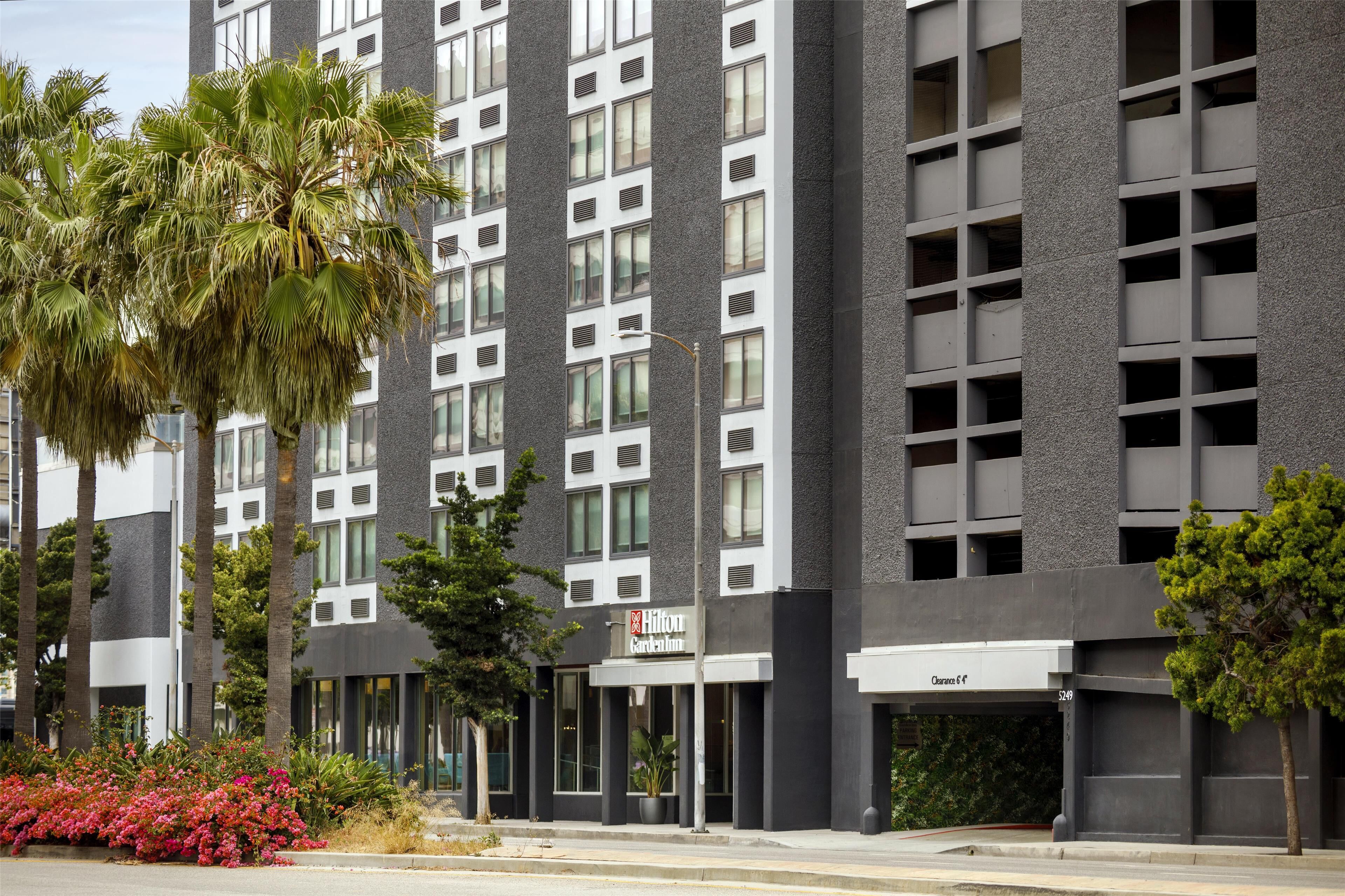 Un moderno edificio de hotel con entrada despejada, ventanas amplias y un letrero visible de Hilton Garden Inn.