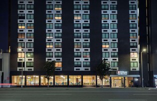 Een Hilton Garden Inn hotel met een moderne gevel, meerdere verdiepingen en een goed verlichte entree.