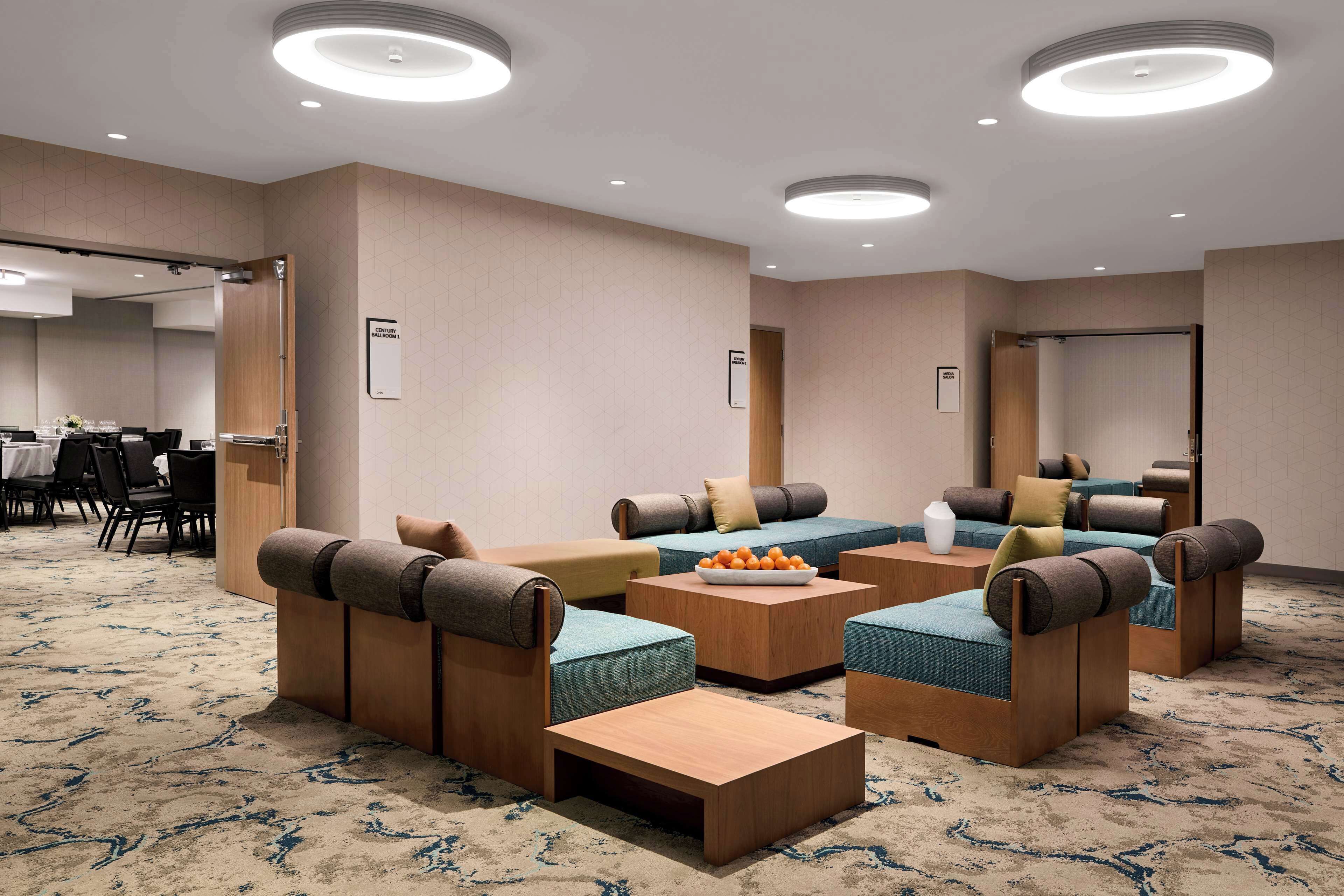 A modern lounge area with sofas and tables, a carpeted floor, and recessed ceiling lighting.