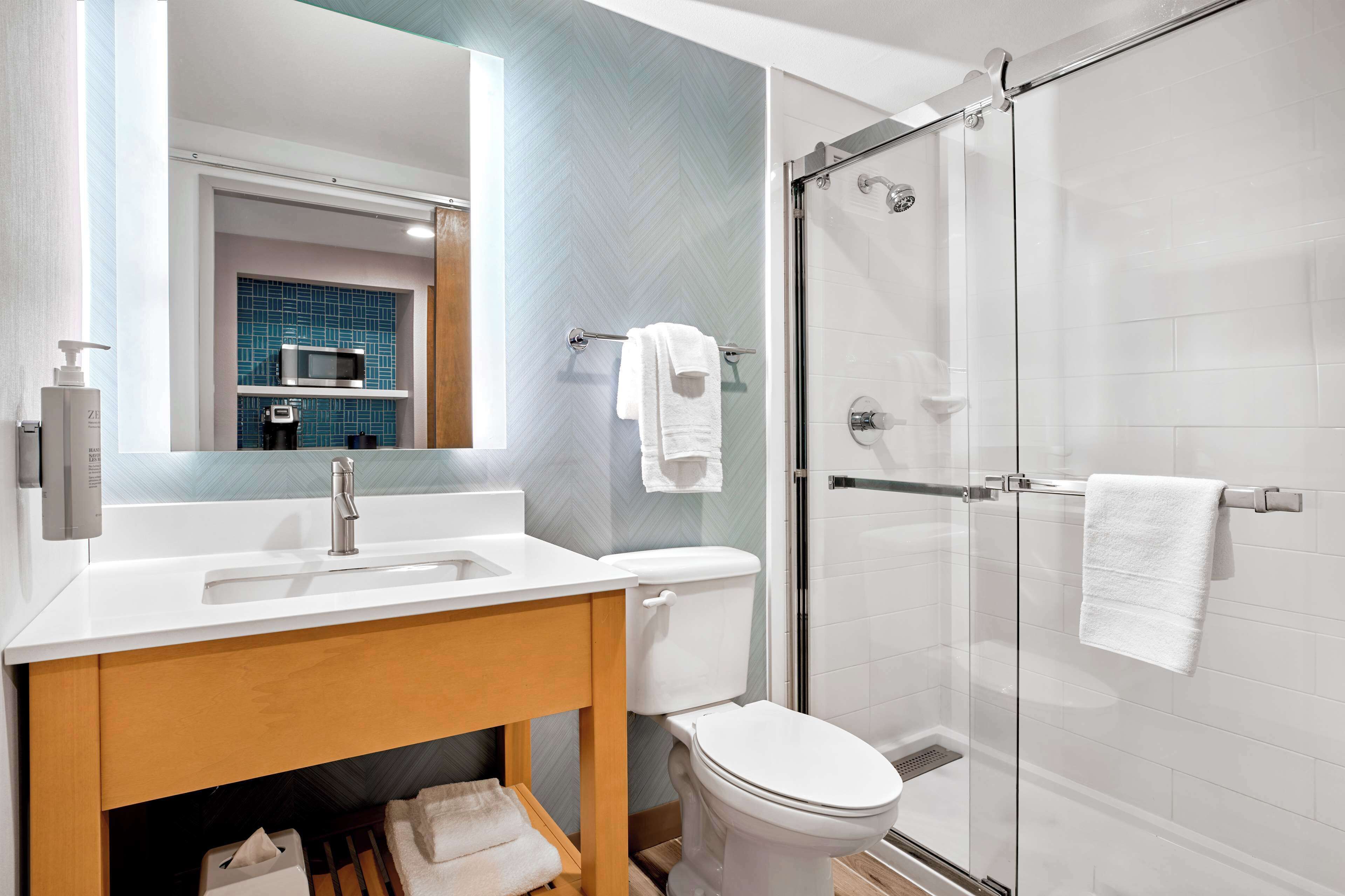 A modern bathroom with a white sink, a toilet, and a glass-enclosed shower.