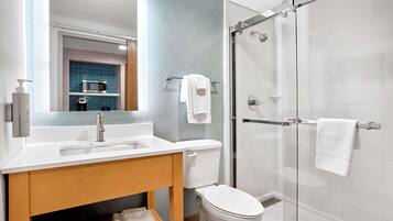 Een moderne badkamer met een wit wastafelmeubel, toilet en een douchecabine met glazen wanden.