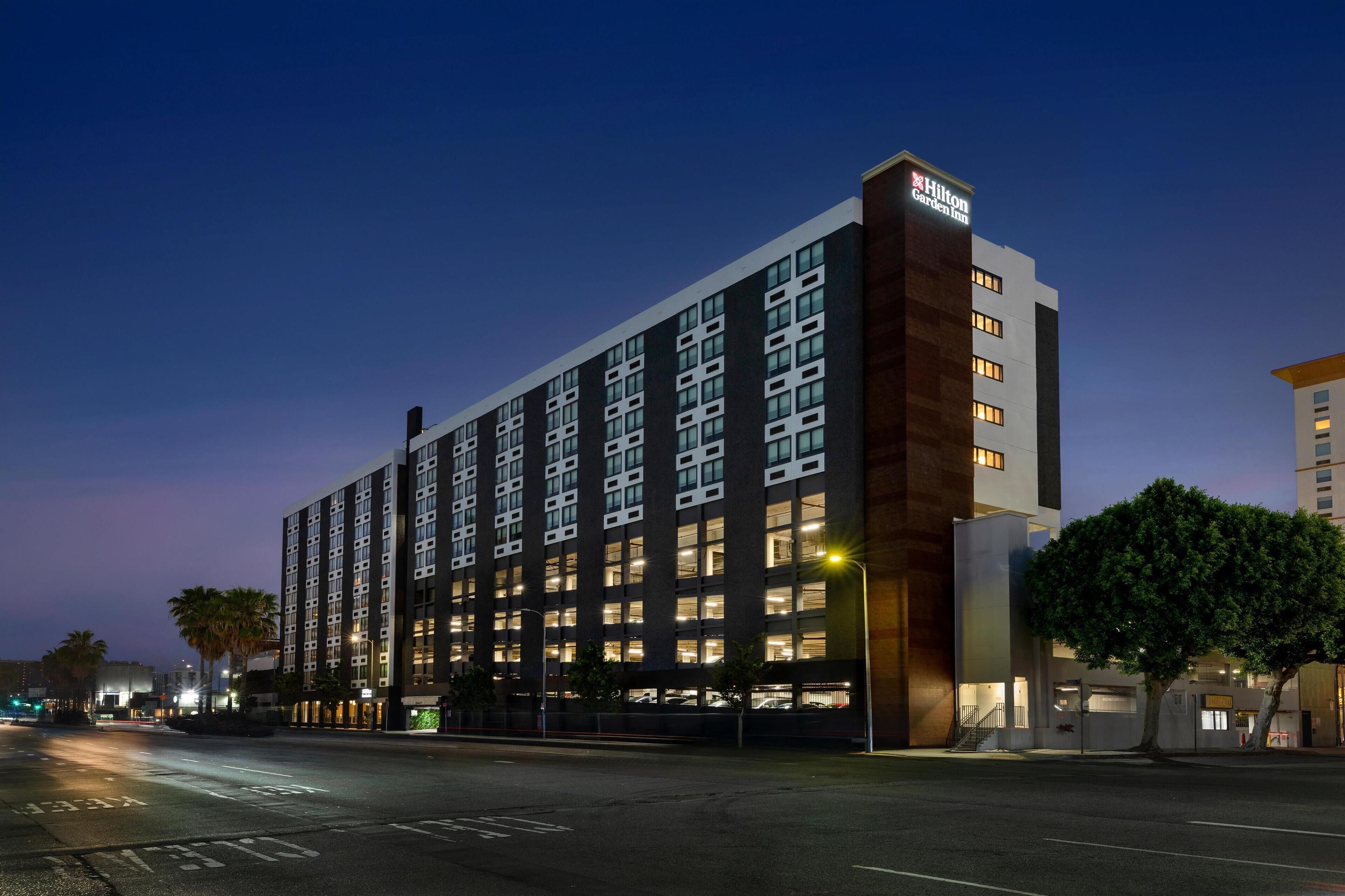 Un hotel moderno con un llamativo letrero de Hilton Garden Inn, varios pisos y un garaje para coches.