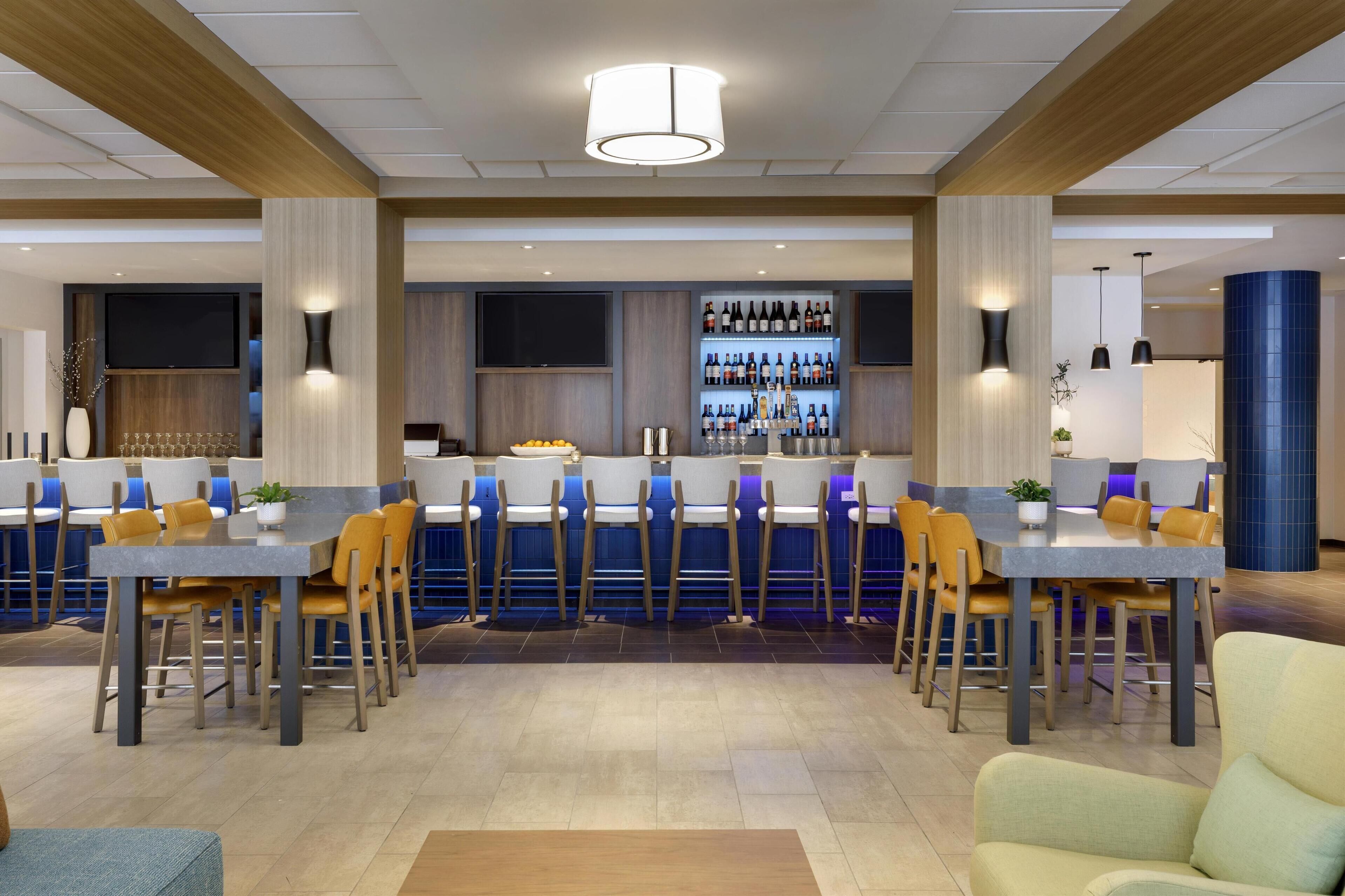 Una moderna hall d'albergo con area bar, posti a sedere e uno schermo televisivo.