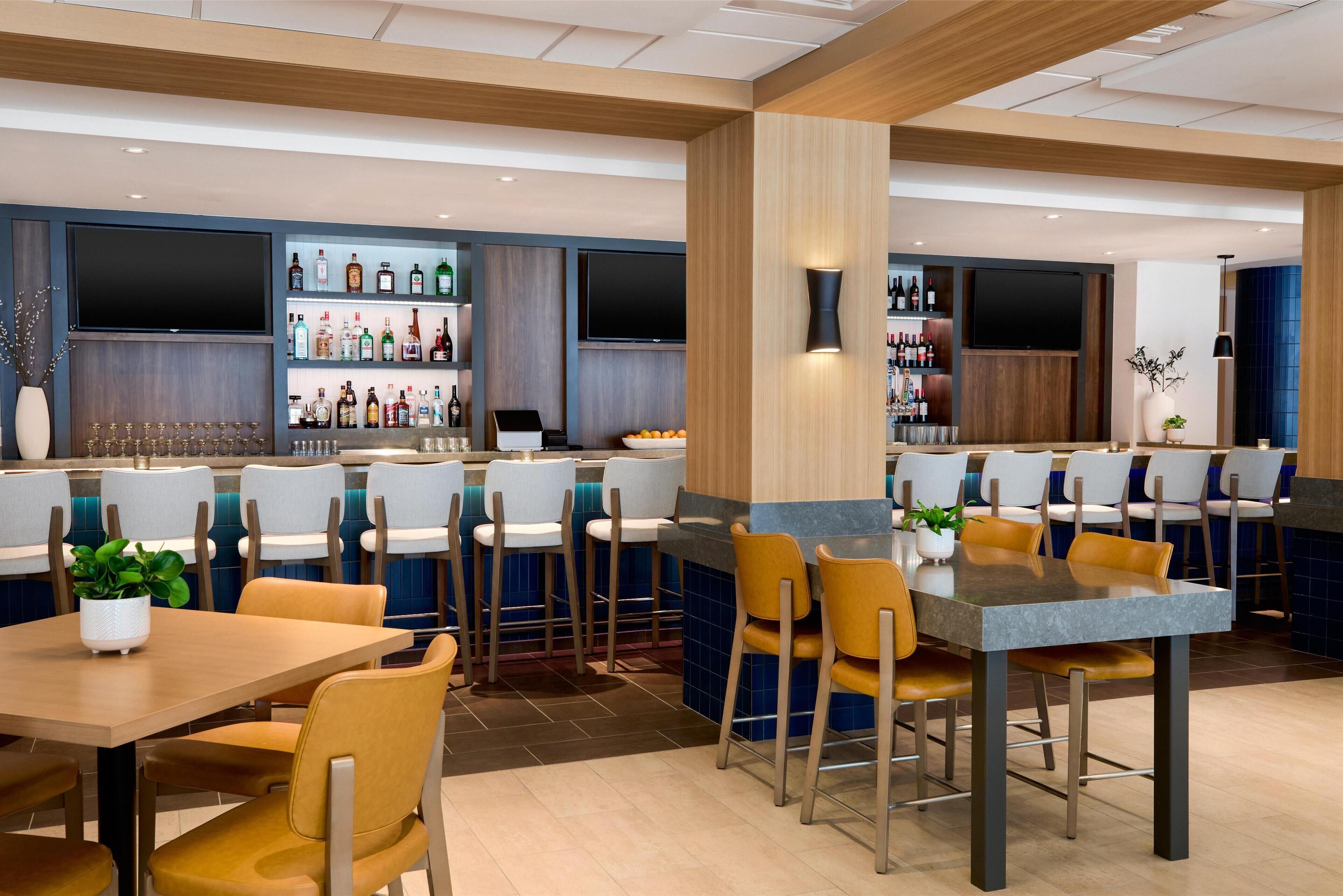 Un espace bar moderne, doté de sièges et d’une variété de bouteilles d’alcool.