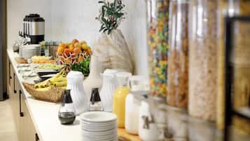 Una mesa de buffet con diversos alimentos, una cafetera y un florero decorativo.