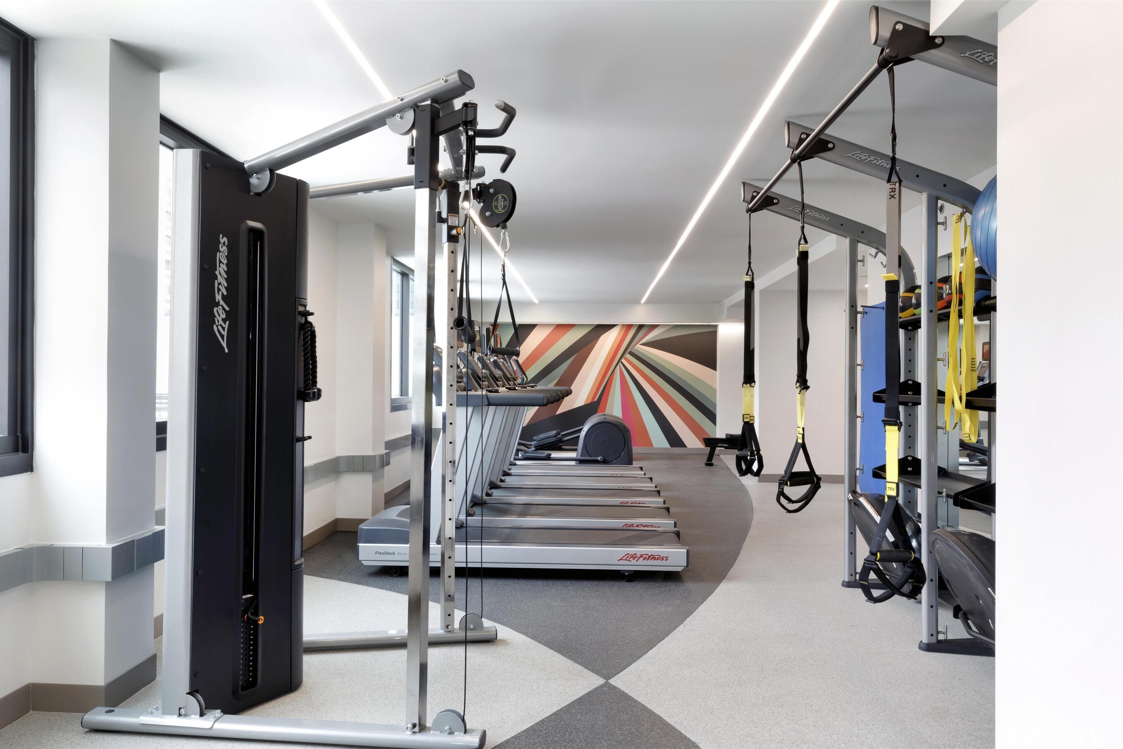 Ein Fitnessstudio mit Laufbändern, Kraftgeräten und Aufhängungsgurten.