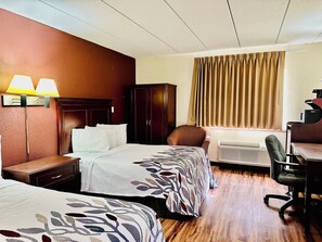 Een hotelkamer met twee bedden, een bureau, een airconditioner en een stoel.