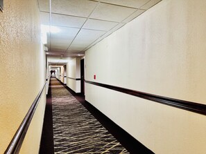 A hotel hallway with carpeted floors, white walls, and doors leading to rooms. - Red Roof Inn Hartford - Vernon (Vernon)