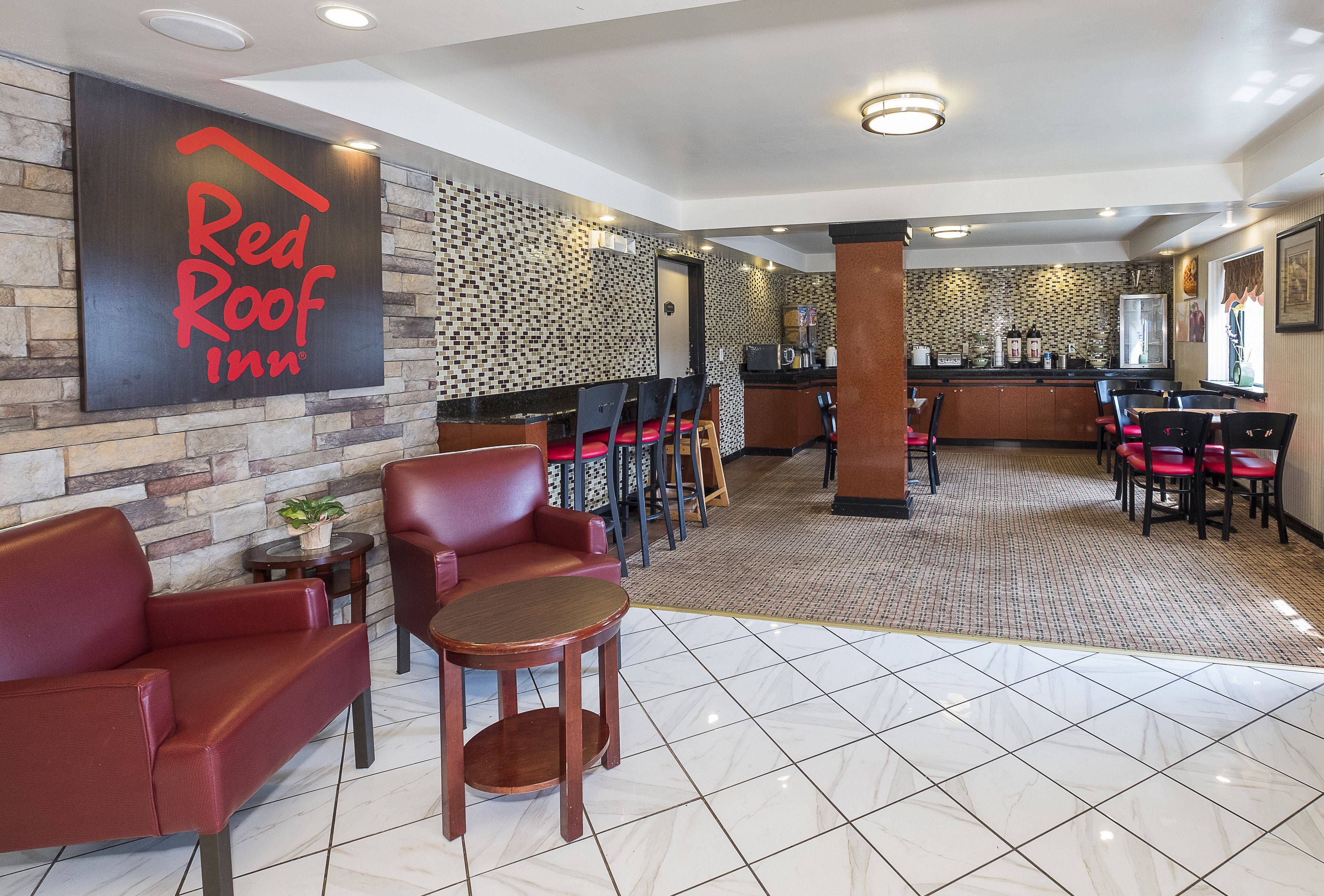 A Red Roof Inn lobby with leather seating, a coffee station, and a patterned wall.
