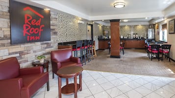 A Red Roof Inn lobby with leather seating, a coffee station, and a patterned wall.