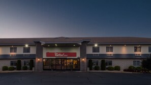 Een Red Roof Inn hotel met een moderne gevel, een ruime entree en een parkeerplaats ervoor.
