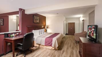 A hotel room with a bed, desk, chair, television, and a mirror.
