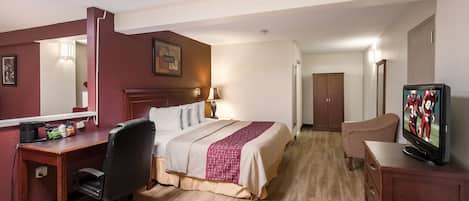A hotel room with a bed, desk, chair, television, and a mirror.