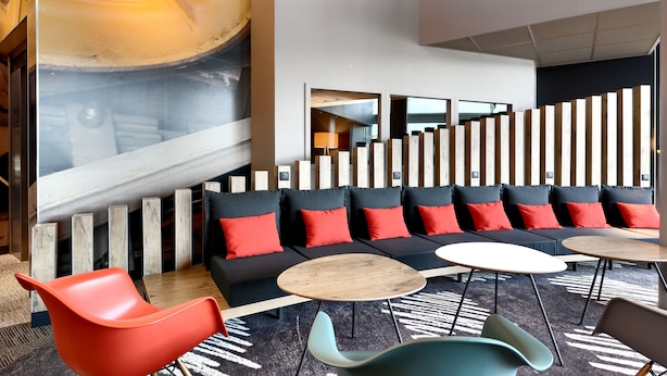 A modern lounge area with a sofa set, round tables, and colorful chairs.