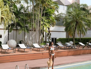 A poolside area with lounge chairs, a pool, and palm trees. - Novotel Abidjan Plateau (Abidjan)