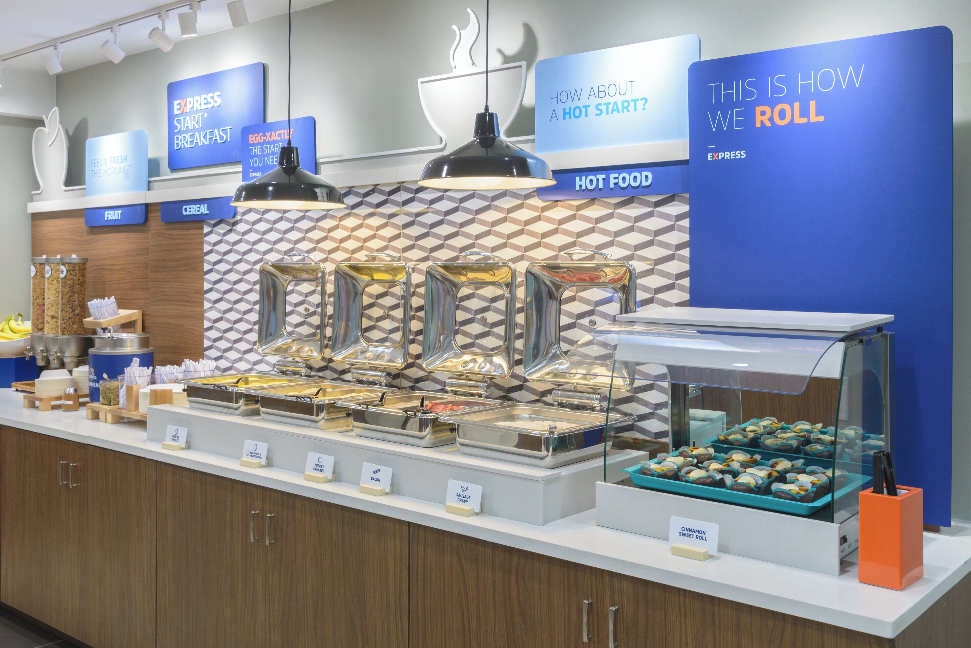 A buffet setup with labeled food stations including breakfast, hot food, and a section for rolls.
