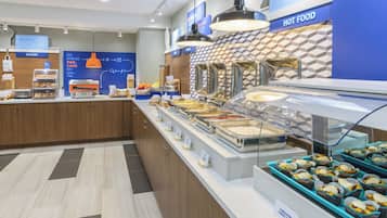 Zona de desayuno tipo buffet con diversas opciones de comida y una sección de panadería.