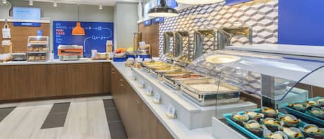 A breakfast buffet area with various food options and a bakery section.