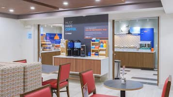 Eine moderne Hotelhalle mit einer Kaffeestation, einer Sitzecke und einer Theke mit Speisen und Getränken.
