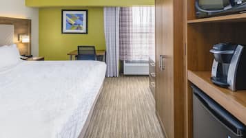 Une chambre d’hôtel équipée d’un lit, d’un bureau, d’une chaise, d’un four à micro-ondes et d’une machine à café.
