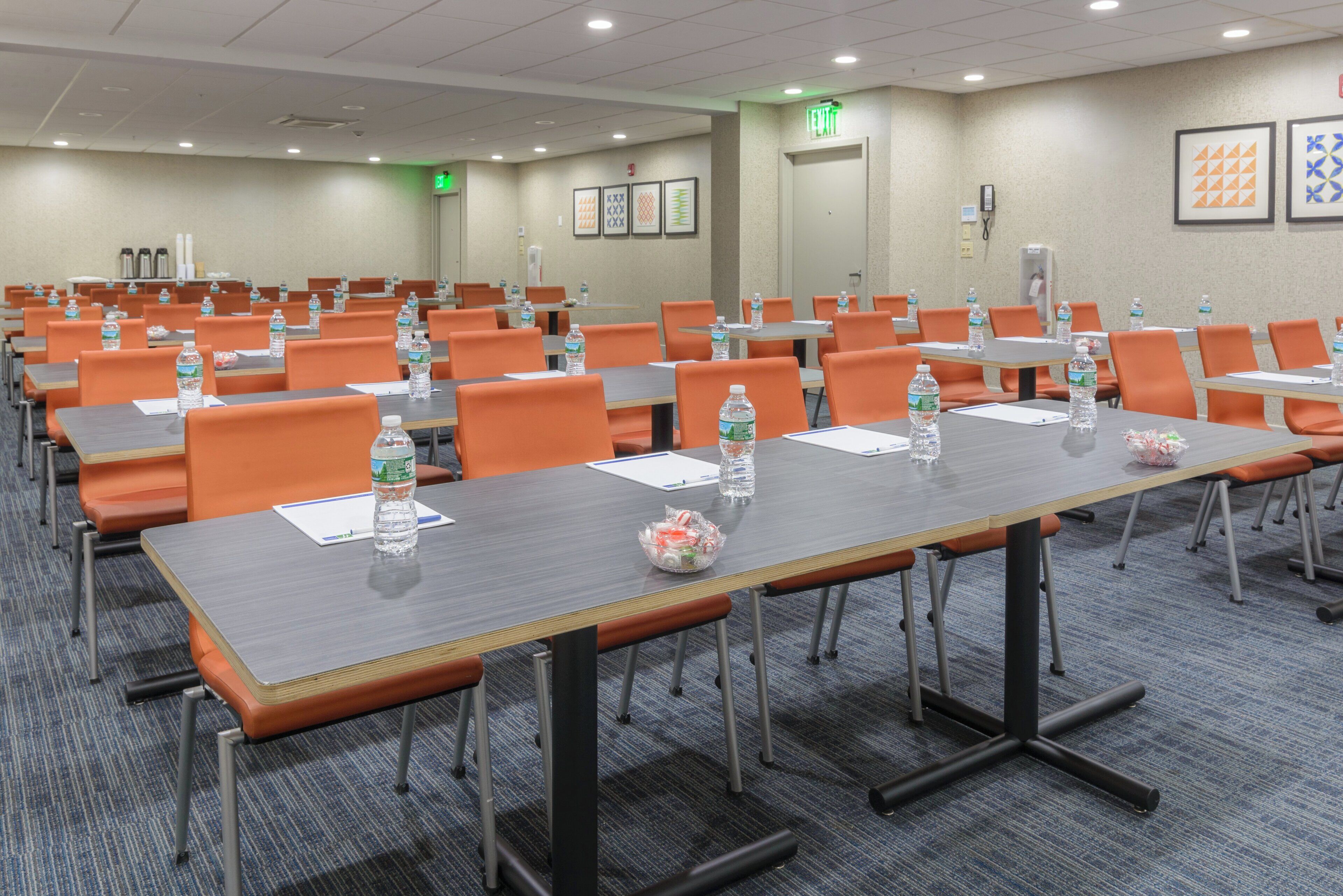 A conference room with rows of tables, chairs, and water bottles.
