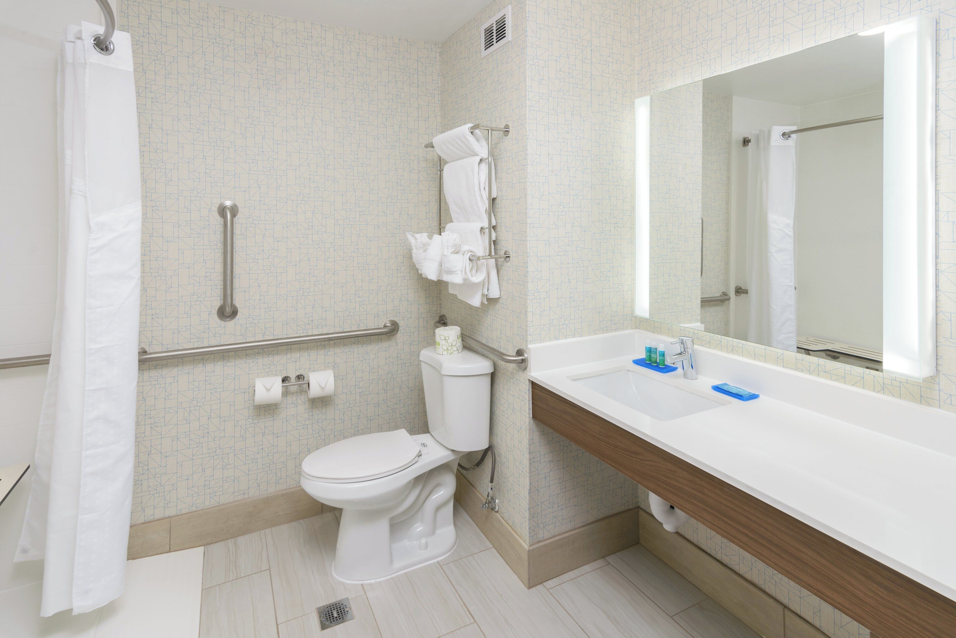 A bathroom with a toilet, a sink, a mirror, and a shower curtain.