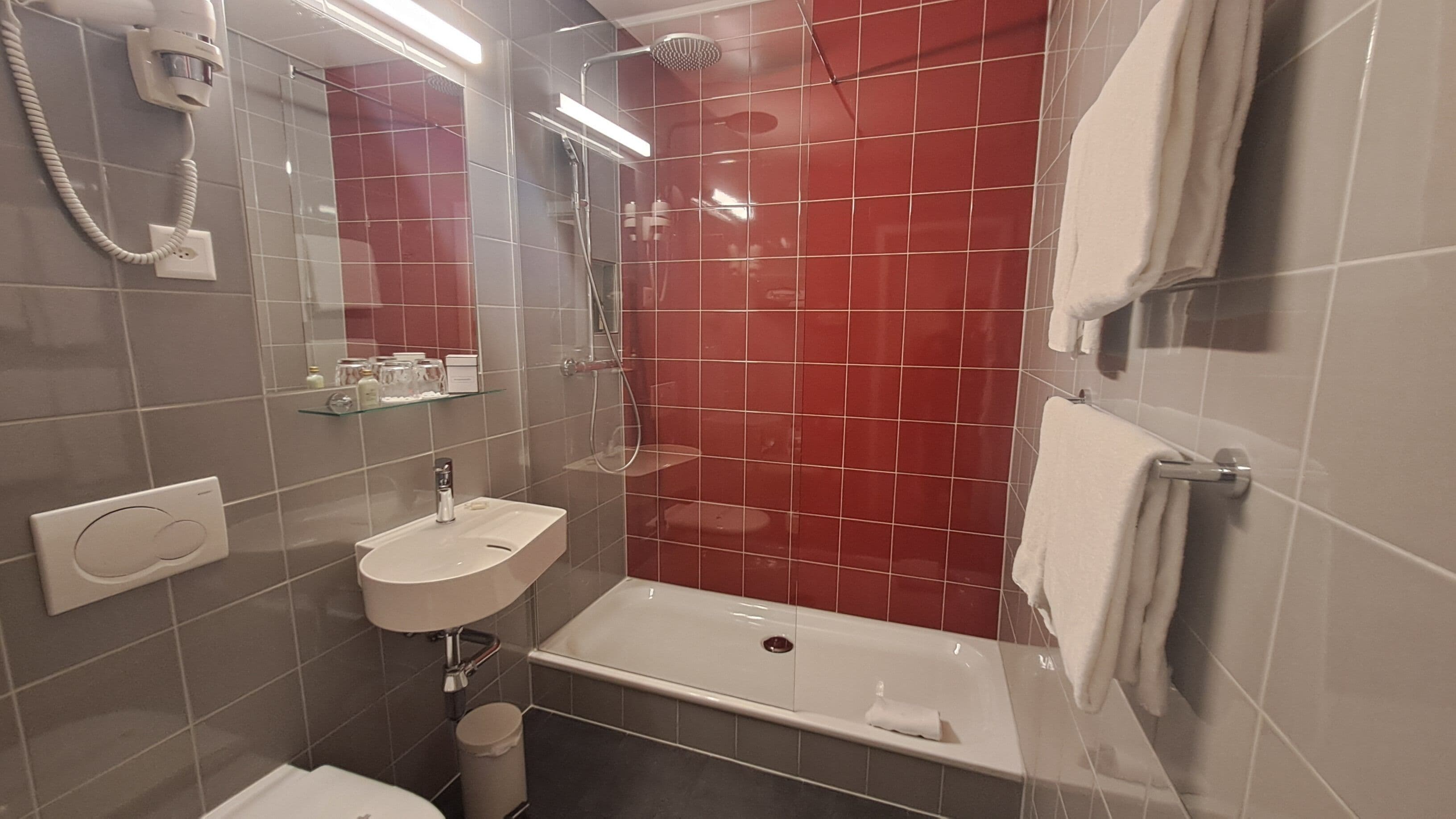 A bathroom with a white sink, a bathtub, a shower, and a mirror.