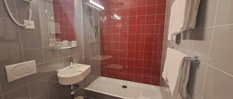 A bathroom with a white sink, a bathtub, a shower, and a mirror.