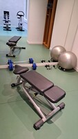 A gym with exercise equipment including a bench, dumbbells, and exercise balls.