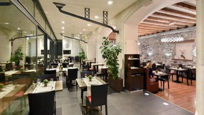 Un restaurant moderne avec des cloisons en verre, des poutres en bois et des plantes en pot.