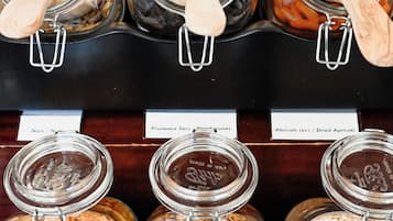 Una exhibición de frutas secas y nueces variadas en frascos de vidrio, con cucharones de madera.
