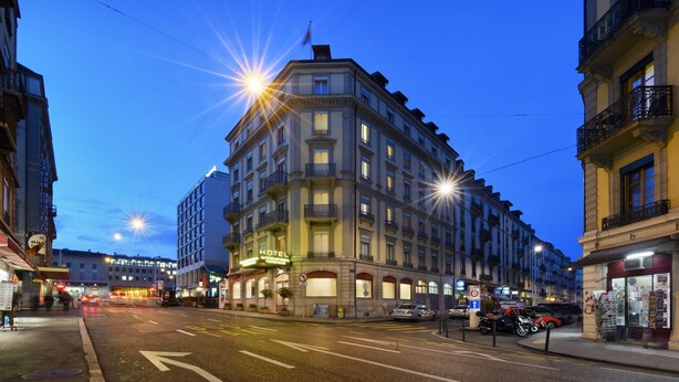 Un hôtel à plusieurs étages, de style architectural classique, qui se distingue par son entrée d’angle imposante et ses nombreux balcons.