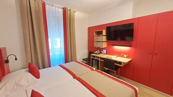 A hotel room with a bed, a desk, a TV, and a wardrobe.