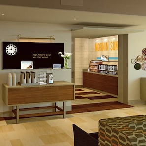 L’intérieur d’un café moderne, avec un comptoir en bois, une horloge et une enseigne sur laquelle on peut lire « MORNING SUN ».