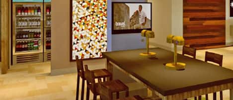 A restaurant with a long table, chairs, a television screen, and a wall with a colorful geometric pattern.